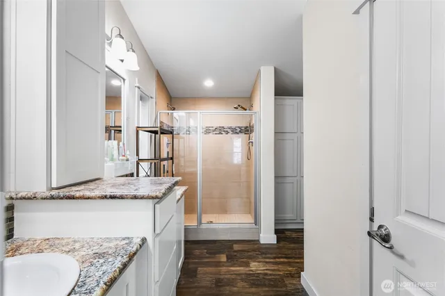 a bathroom with a granite countertop sink a mirror and shower