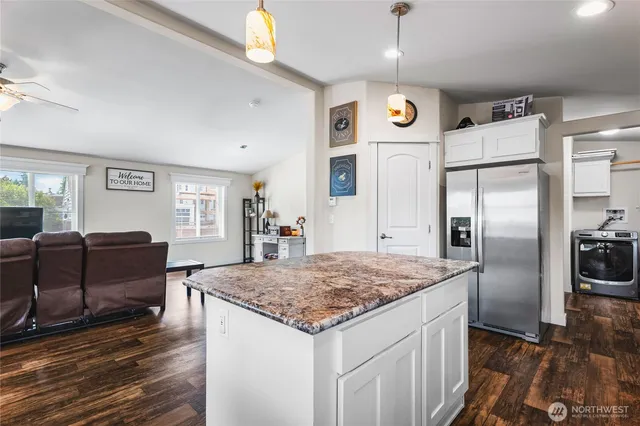 a kitchen with stainless steel appliances granite countertop a refrigerator oven a sink dishwasher a dining table and chairs with wooden floor