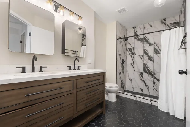 a bathroom with a double vanity sink mirror and shower