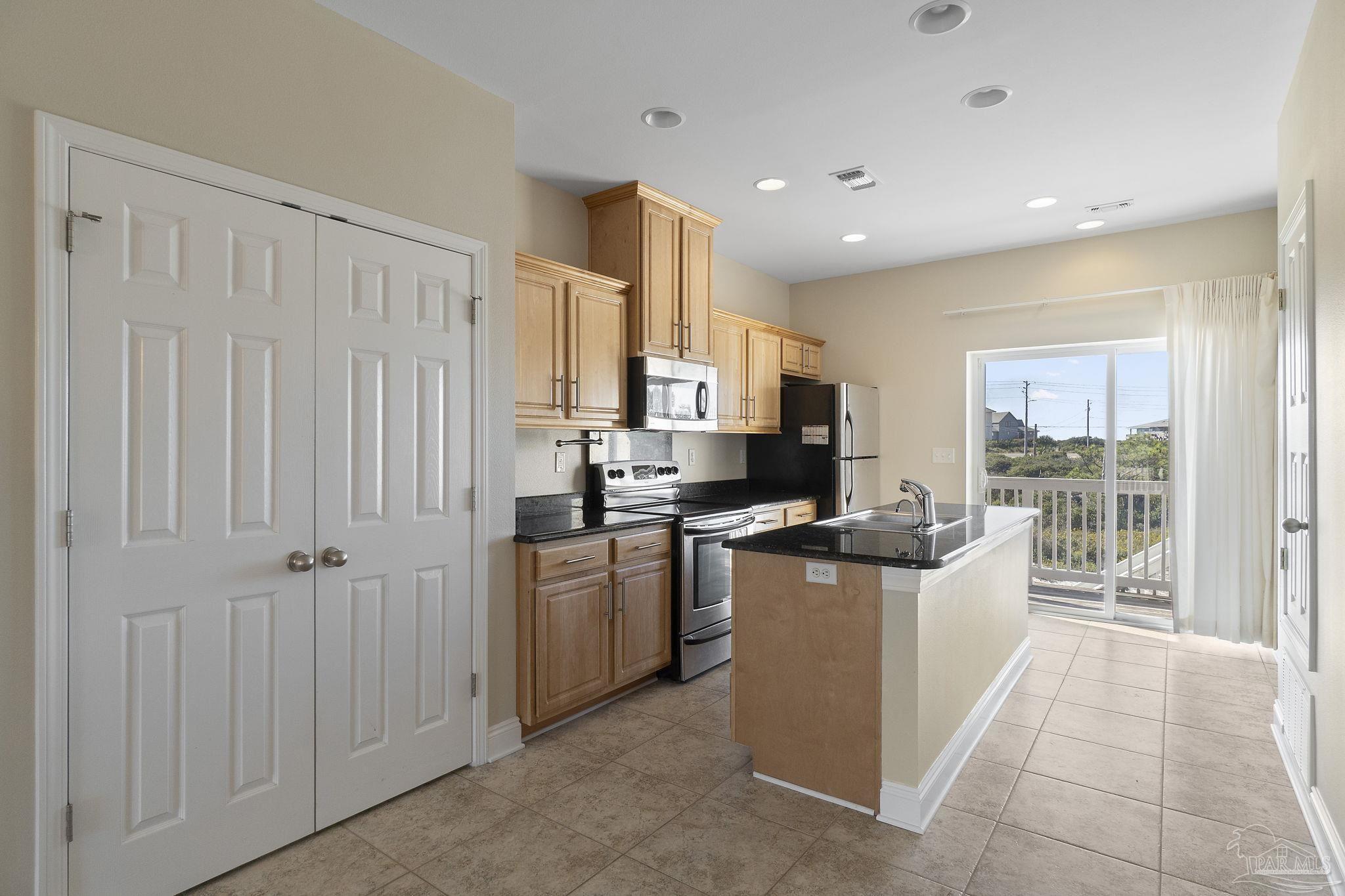 16300 Perdido Key Drive, Unit 20 Perdido Key, FL 32507 - Photo 17 of 47 a kitchen with stainless steel appliances granite countertop a refrigerator oven a sink dishwasher and white cabinets with wooden floor