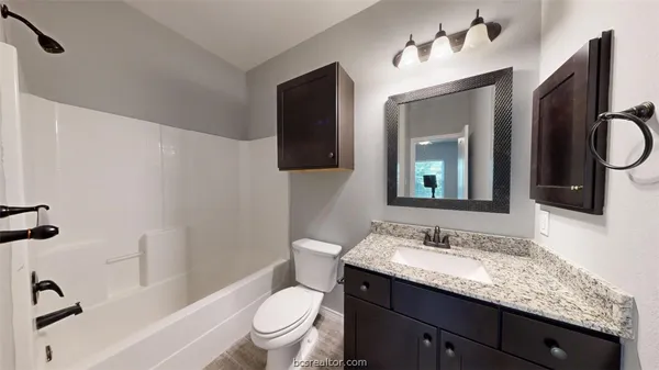 a bathroom with a granite countertop sink toilet and mirror