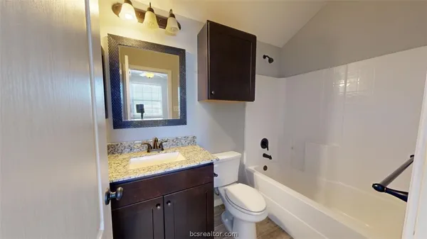 a bathroom with a granite countertop sink toilet and mirror