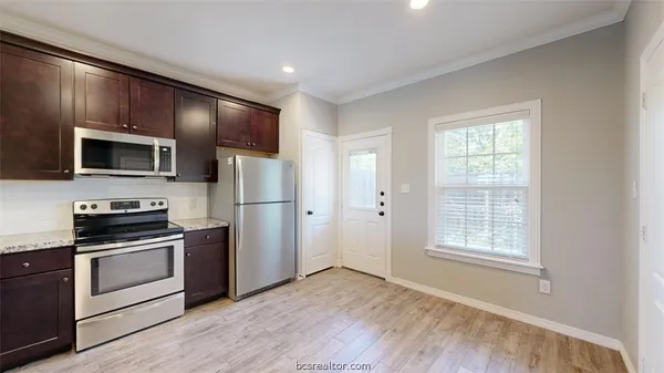 a kitchen with granite countertop a refrigerator and a stove top oven