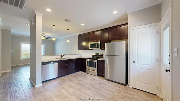 a kitchen with stainless steel appliances kitchen island granite countertop a refrigerator a sink dishwasher a stove and a refrigerator with wooden floor