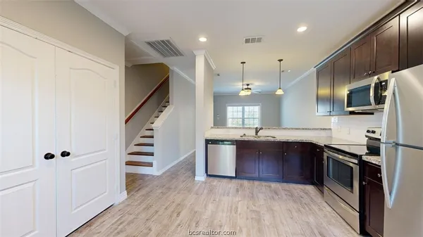 a kitchen with stainless steel appliances granite countertop a sink a stove and refrigerator