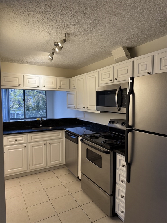 a kitchen with granite countertop a refrigerator stove and sink