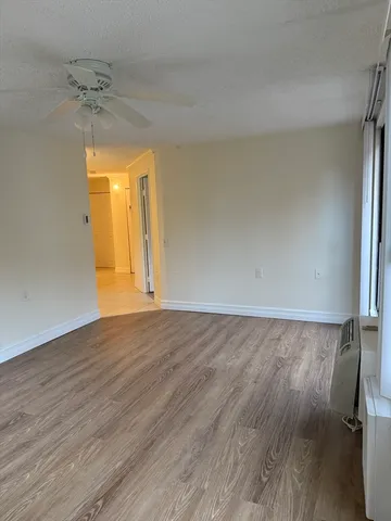 an empty room with a chandelier fan and wooden floor