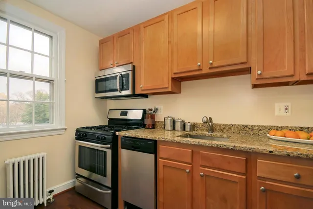 a kitchen with stainless steel appliances granite countertop a sink a stove a microwave cabinets and a window