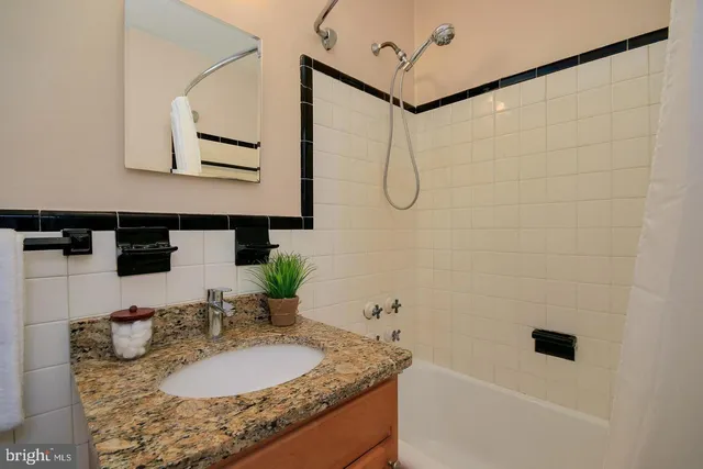 a bathroom with a granite countertop sink a mirror and shower