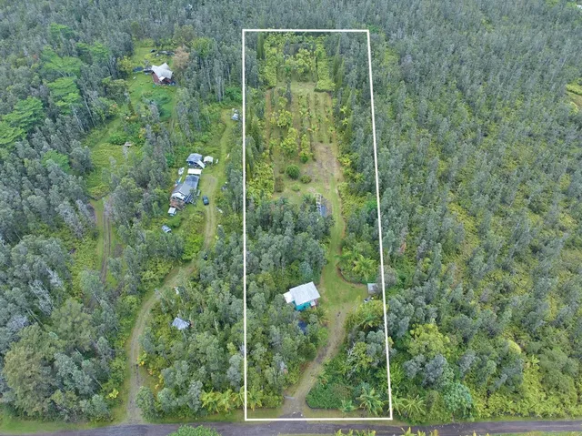 a view of a house with large trees and a wooden fence