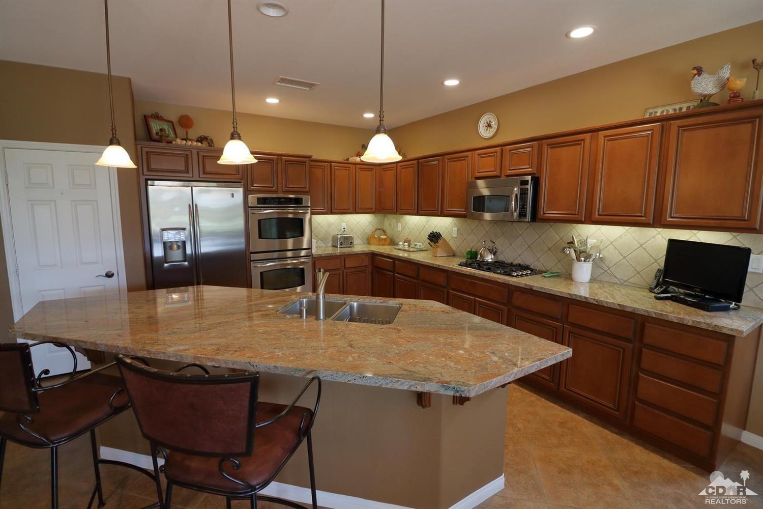 81757 Rustic Canyon Drive La Quinta, CA 92253 - Photo 11 of 40 a kitchen with stainless steel appliances granite countertop a sink a stove and a refrigerator