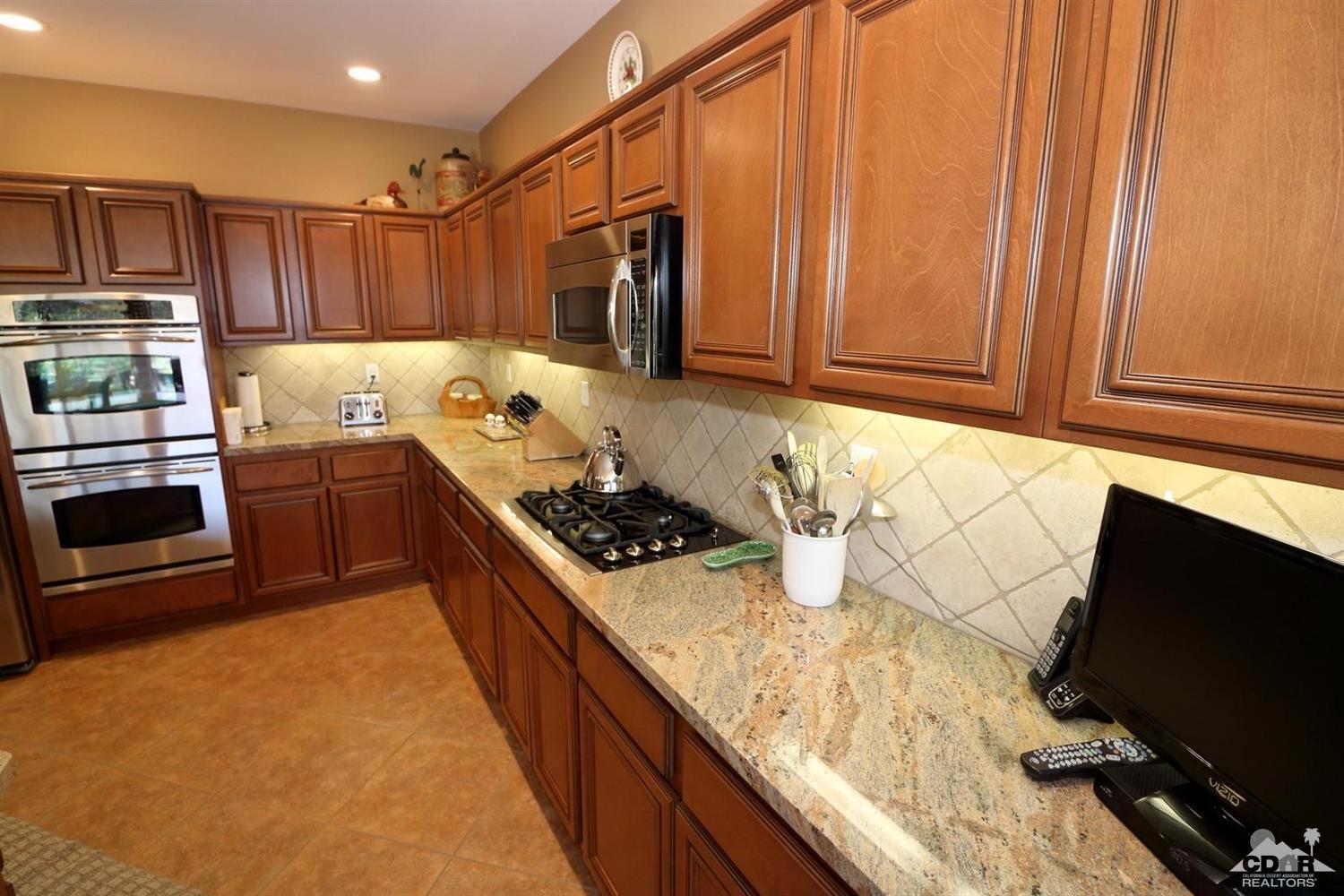 81757 Rustic Canyon Drive La Quinta, CA 92253 - Photo 12 of 40 a kitchen with stainless steel appliances granite countertop a stove and a refrigerator