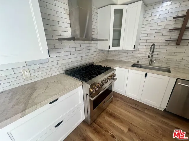 a kitchen with granite countertop a sink a stove and cabinets