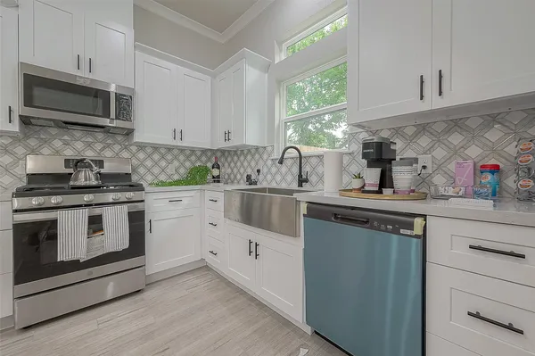 a kitchen with white cabinets appliances a sink and a window