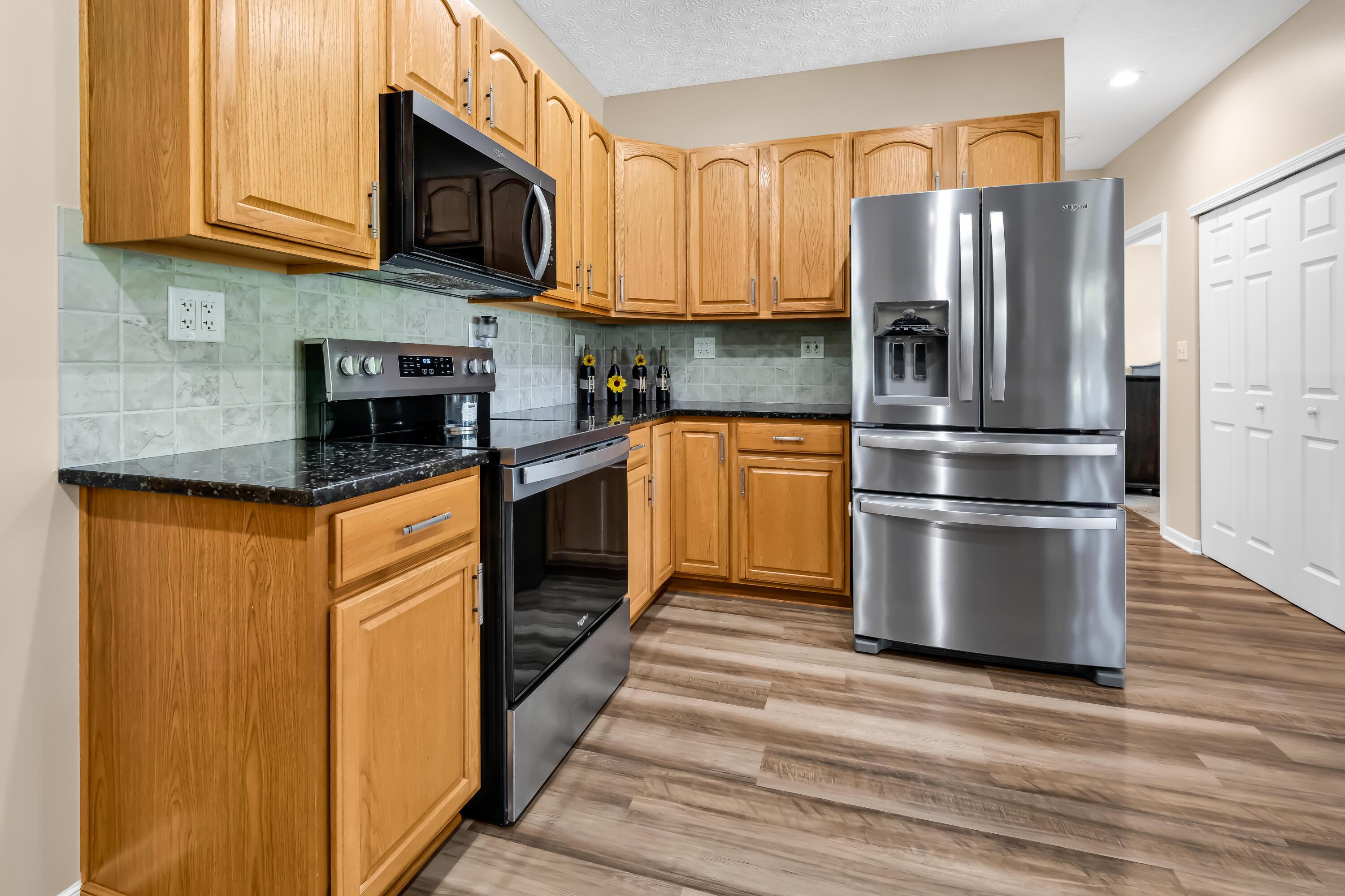 14396 Blamer Road Johnstown, OH 43031 - Photo 17 of 48 • Luxury vinyl plank flooring
• Tan painted walls
• Granite countertops
• New Whirlpool® refrigerator
~ 2025
• New Whirlpool® microwave
~ 2025
• New Whirlpool® electric
range ~ 2025
• New Whirlpool® dishwasher
~ 2025
• Peninsula with breakfast bar
ledge
• Double bowl, stainless steel
sink with sprayer
• New disposal ~ 2026
• Tile backsplash
• Raised panel cabinets