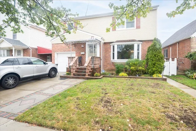 a view of a white house with a large windows and a yard with plants