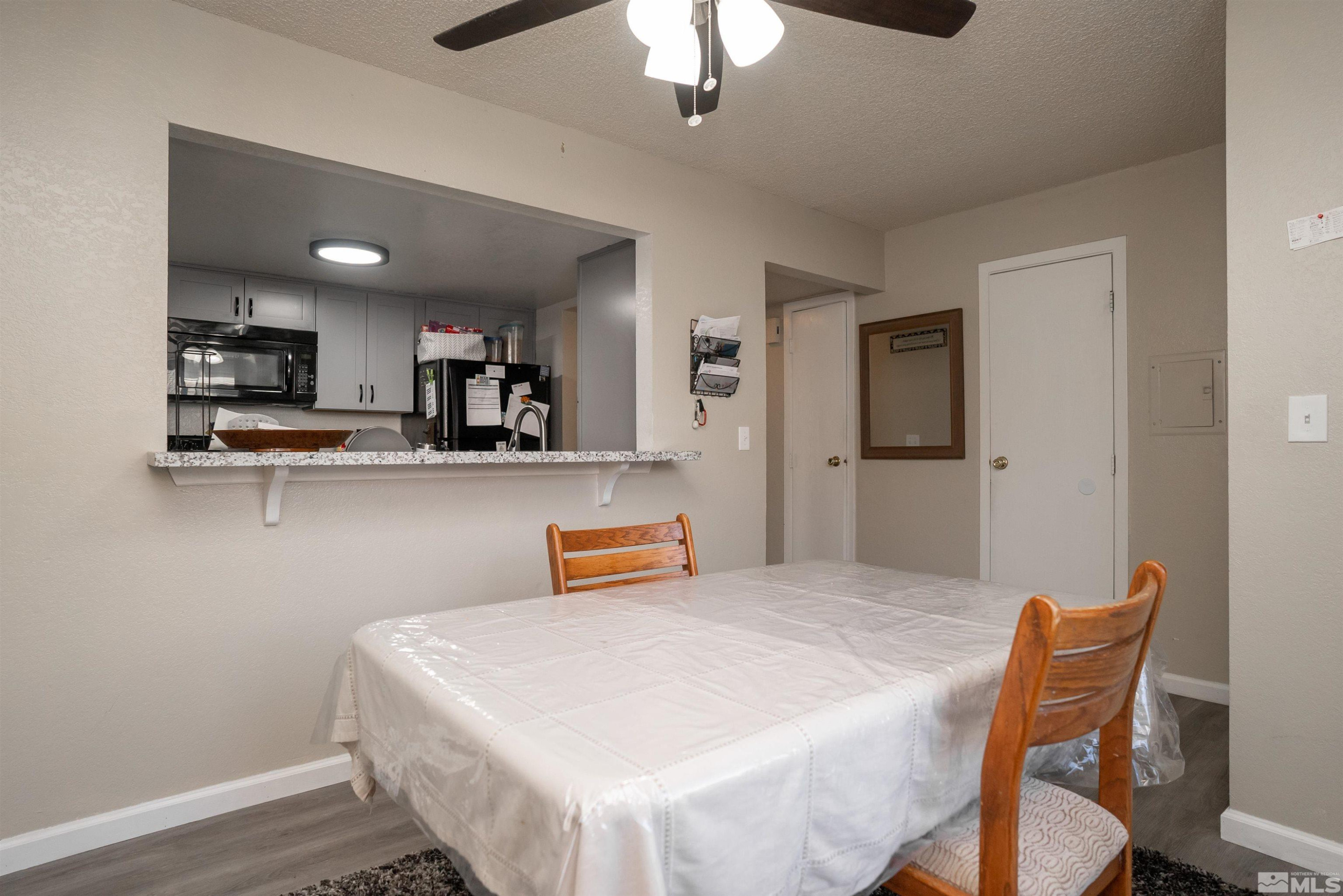 13864 Lear Boulevard Reno, NV 89506 - Photo 3 of 31 a kitchen with stainless steel appliances kitchen island granite countertop a refrigerator a stove a sink a dining table and chairs with wooden floor