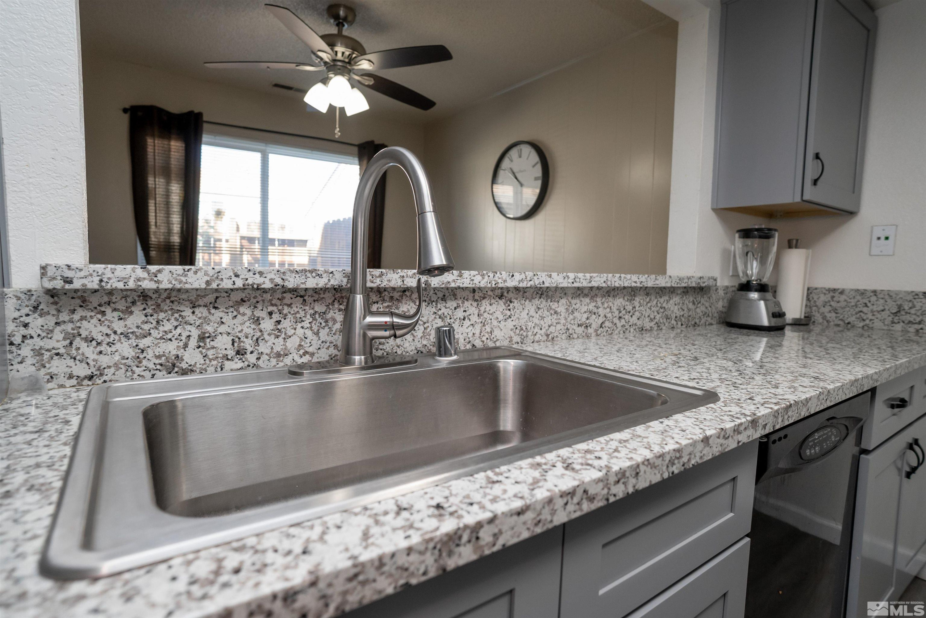13864 Lear Boulevard Reno, NV 89506 - Photo 9 of 31 a kitchen with granite countertop a sink stainless steel appliances and a counter space