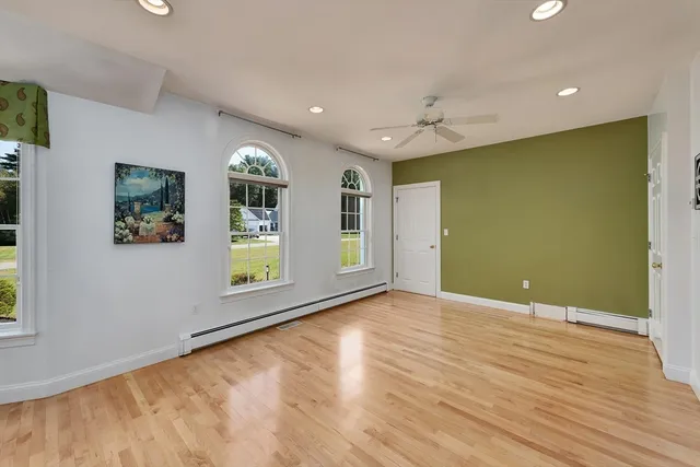a view of an empty room with window and wooden floor