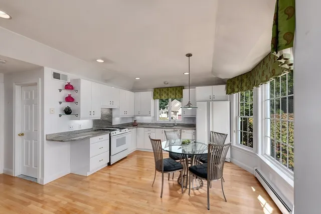 a kitchen with stainless steel appliances kitchen island granite countertop a table chairs and a refrigerator