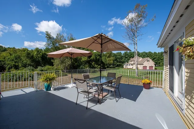 a view of a patio with couches table and chairs under an umbrella with a fire pit