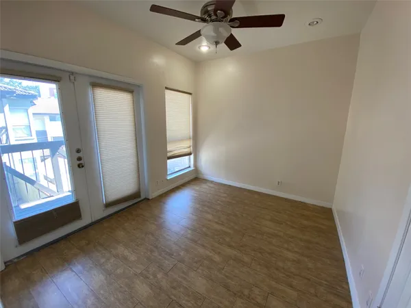 an empty room with wooden floor fan and windows