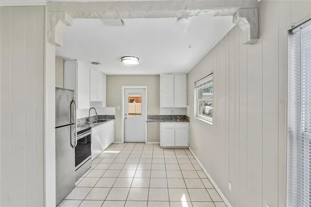 a large white kitchen with a stove a sink dishwasher and a refrigerator with white cabinets