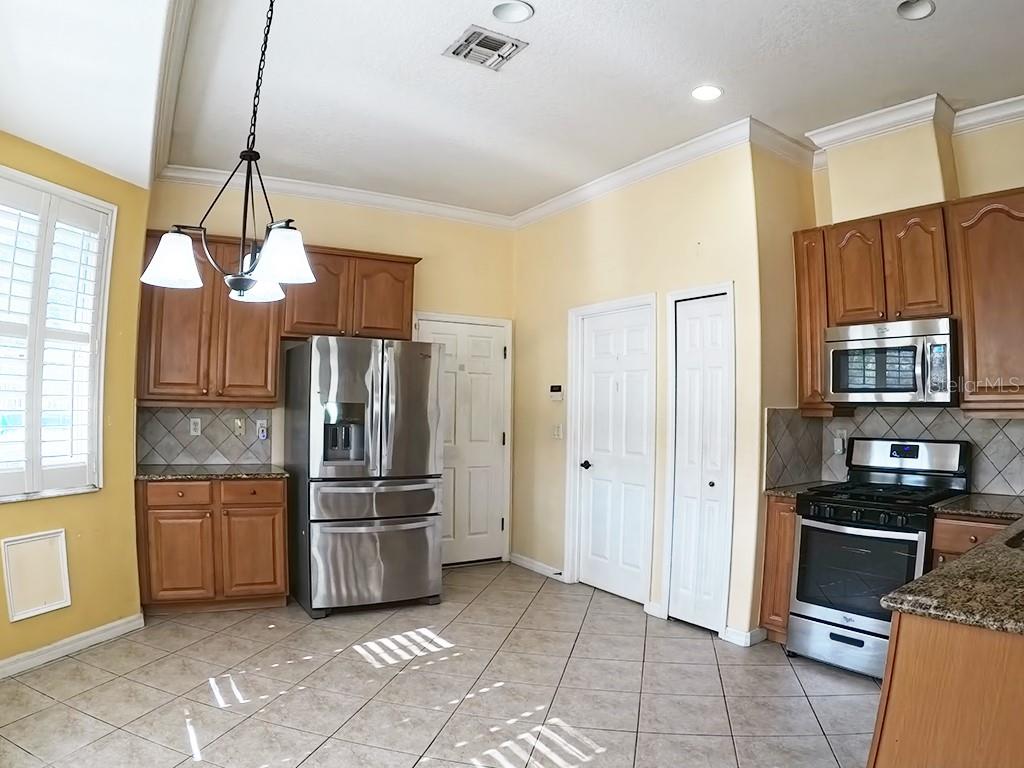 100 Flame Vine Way Groveland, FL 34736 - Photo 14 of 38 a kitchen with stainless steel appliances a refrigerator and a stove top oven