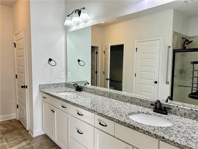 a bathroom with a granite countertop double vanity sink and mirror