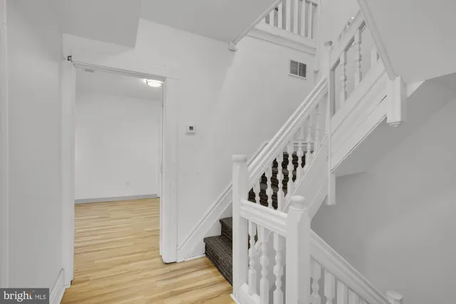 a view of staircase with wooden floor and white walls