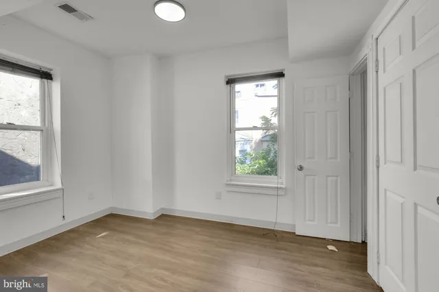an empty room with wooden floor and windows