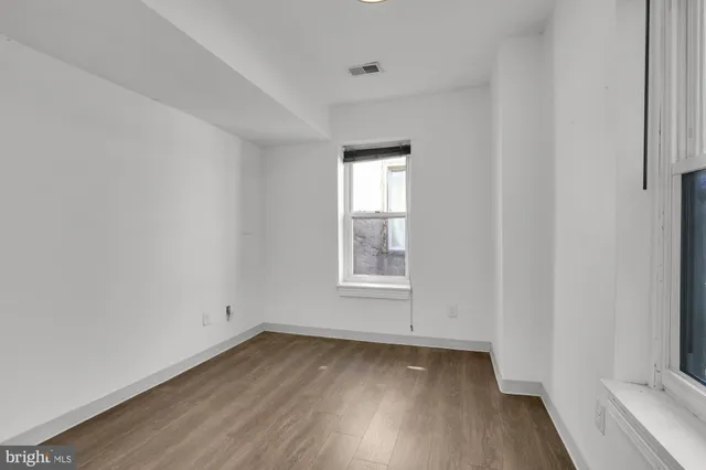 an empty room with wooden floor and window