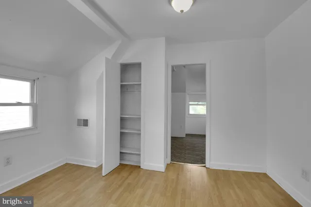 an empty room with wooden floor & closet and windows