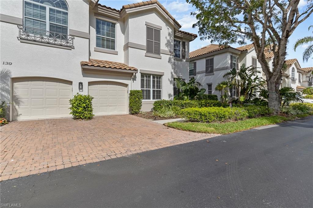 137 Colonade Circle, Unit 601 Naples, FL 34103 - Photo 24 of 28 a front view of a house with a yard and garage