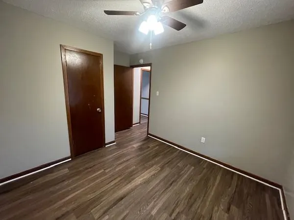 an empty room with wooden floor closet and windows