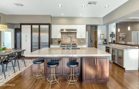 a kitchen with stainless steel appliances granite countertop table chairs stove and sink