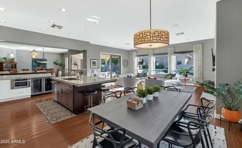 a view of a dining room and livingroom with furniture wooden floor a rug a painting and a chandelier