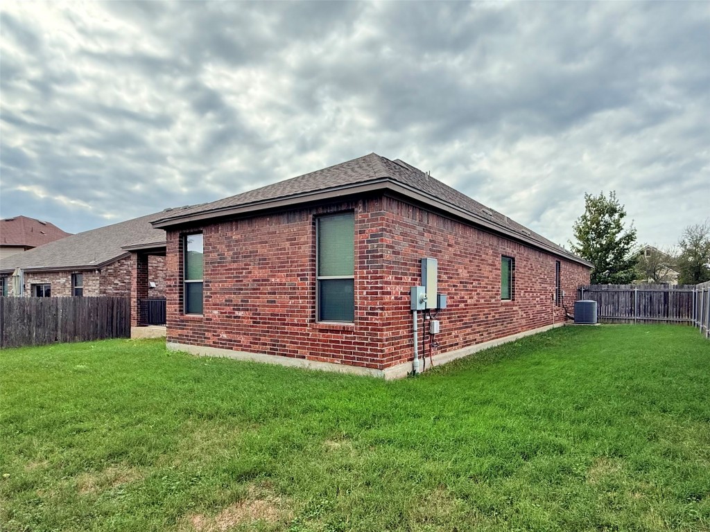 1140 Yellow Iris Road Leander, TX 78641 - Photo 22 of 23 View of property exterior featuring a fenced backyard, brick siding, and a shingled roof
