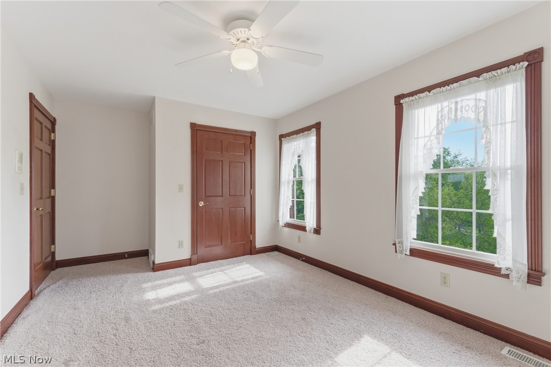 2184 Brenner Road Northeast Carrollton, OH 44615 - Photo 30 of 50 Bright room featuring two large windows, white walls, light carpet flooring, and a ceiling fan with light fixture