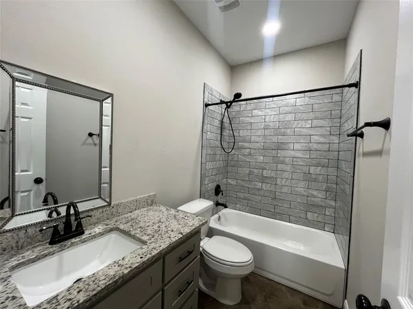 a bathroom with a granite countertop sink toilet mirror and bathtub