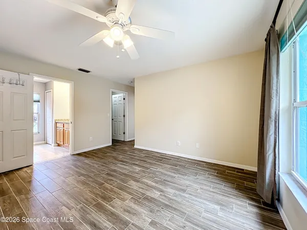 a view of an empty room with wooden floor and a window