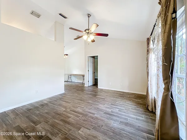 a view of empty room with wooden floor and fan