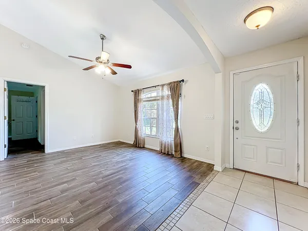 an empty room with wooden floor chandelier fan and windows