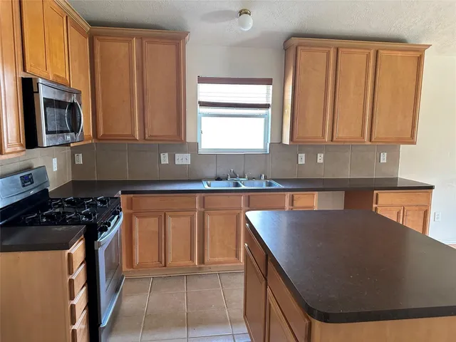 a kitchen with granite countertop a stove a sink and a microwave