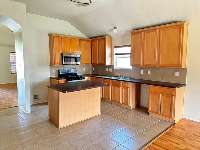 a kitchen with stainless steel appliances granite countertop a stove a sink and a refrigerator