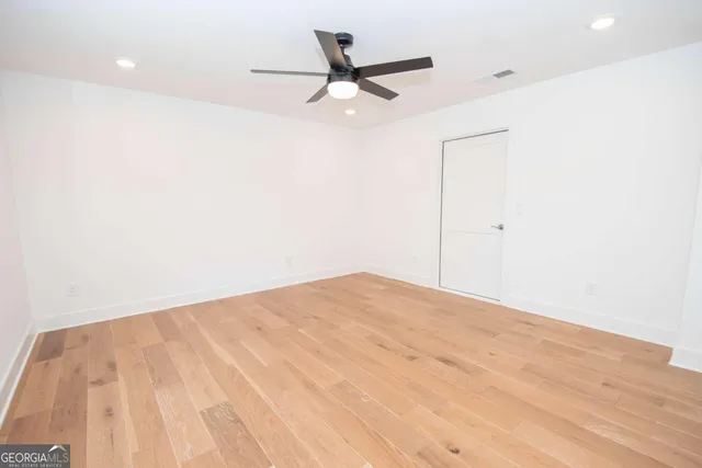 a view of a room with wooden floor and a ceiling fan