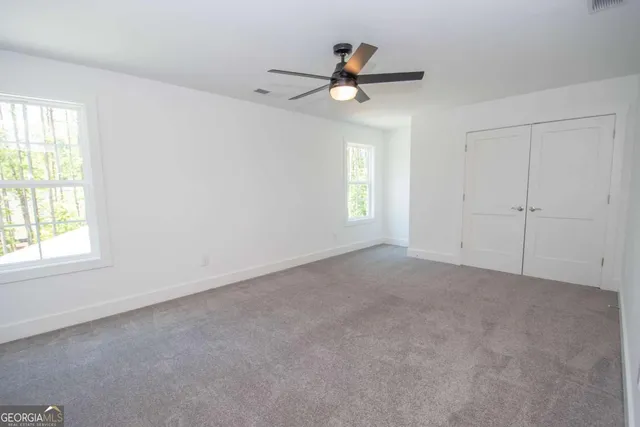 an empty room with a ceiling fan and carpet