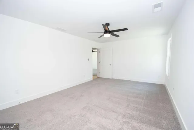 an empty room with a window and a fan