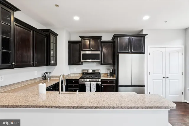 a kitchen with stainless steel appliances granite countertop a refrigerator a stove a sink and a microwave