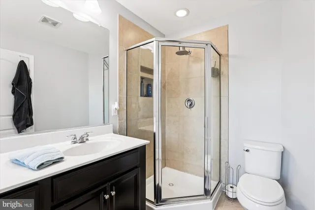 a bathroom with a shower sink vanity mirror and toilet